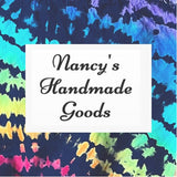 Script reads Nancy's Handmade Goods on a background of tie dye design in rainbow and black colors